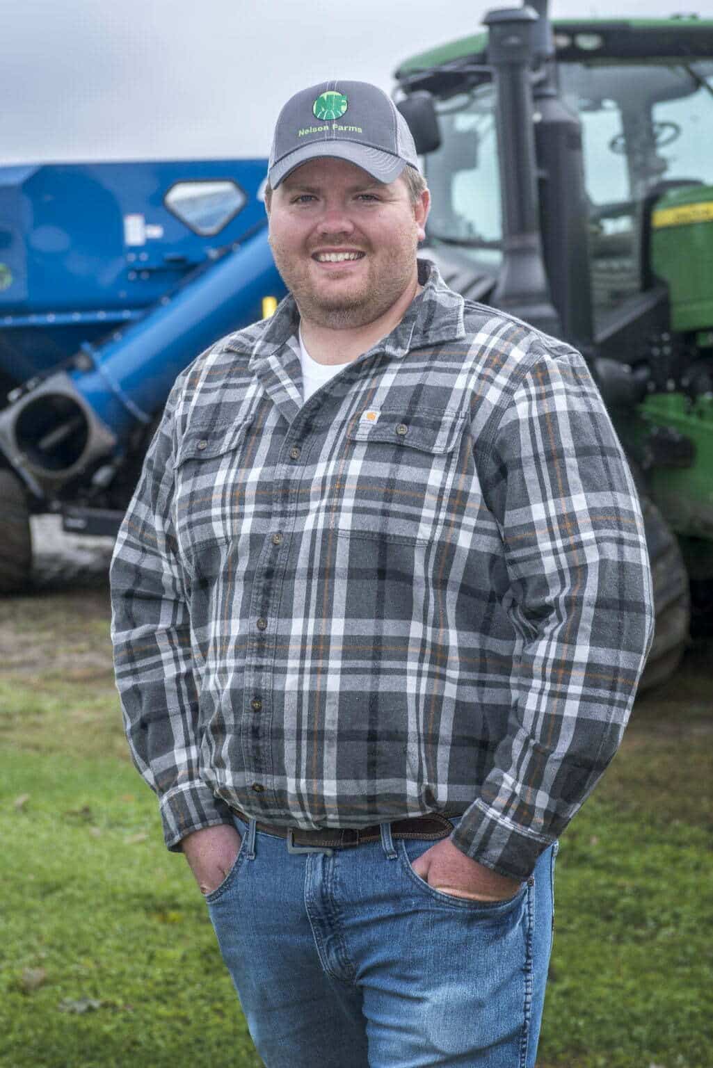 Man smiling in front of John Deer tractor