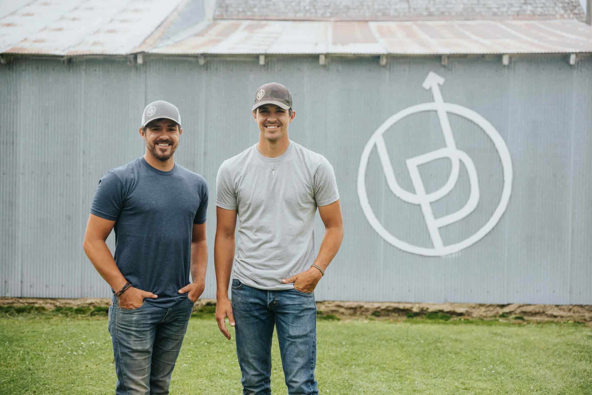 two men standing in front of barn