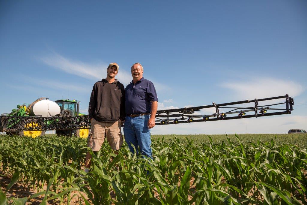 Photo of two men standing in a corn field