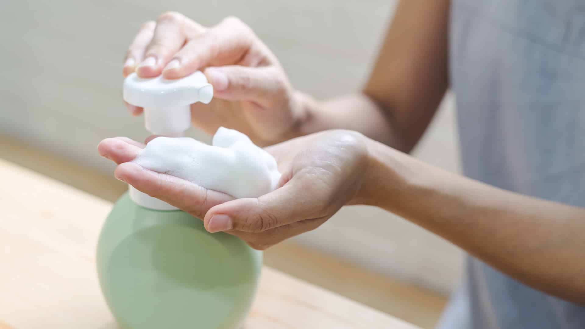 A woman pumps foaming soap onto her hands.