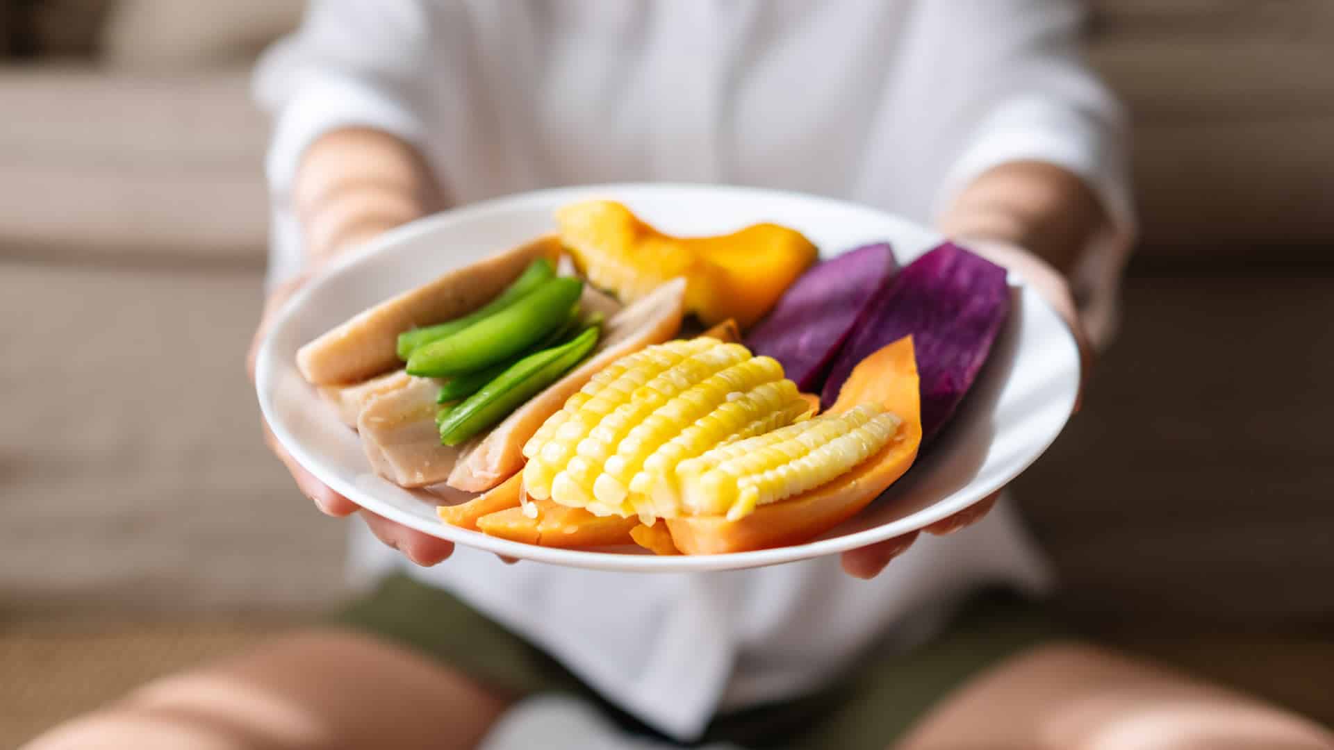 sliced vegetables on a white plate being held out