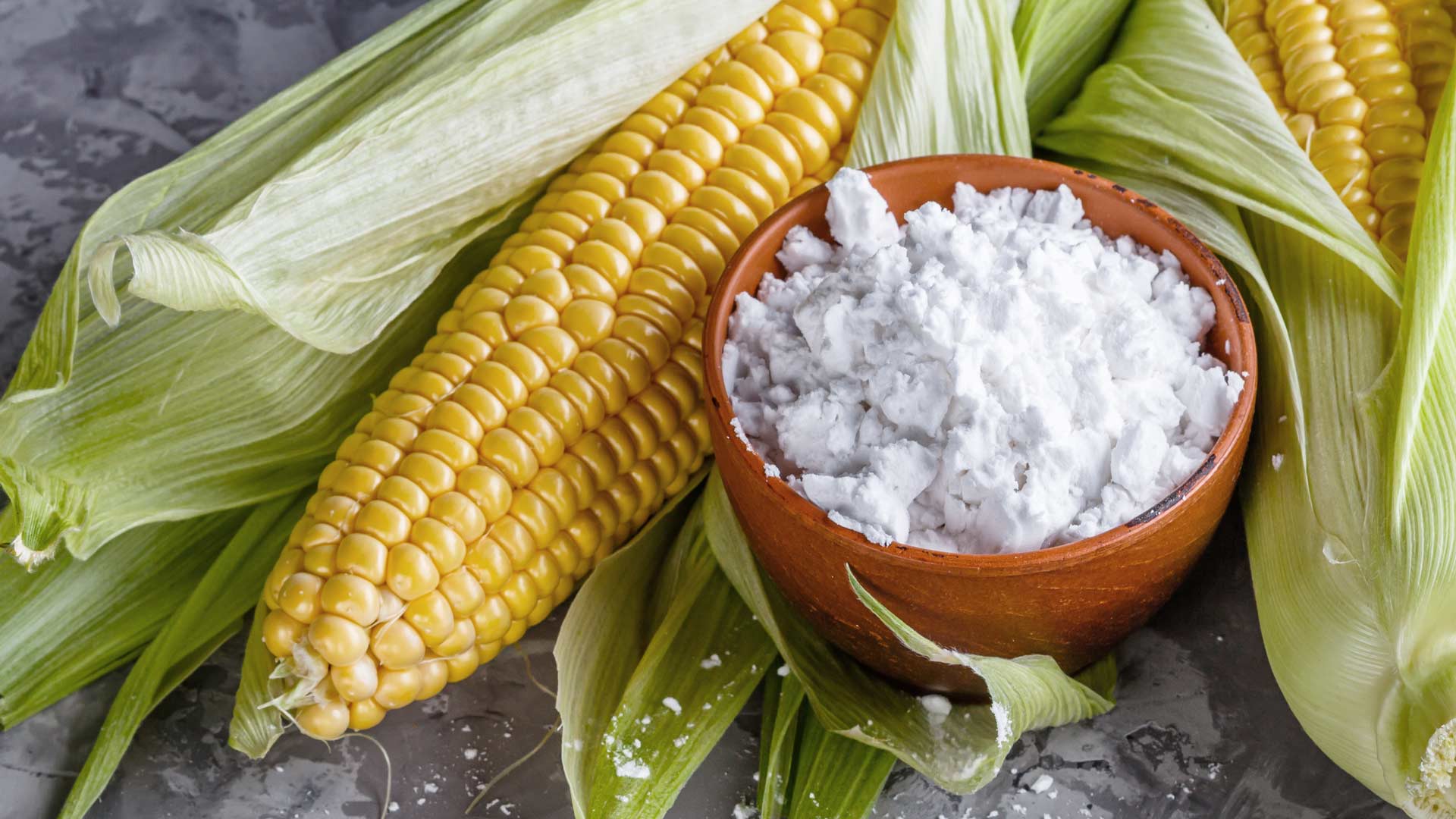 Cob of corn next to a bowl of feta cheese