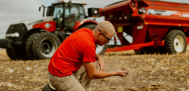 Farmer inspecting soil in corn field