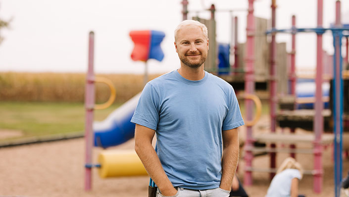 Logan Reed standing near a playground with his kids playing in the background