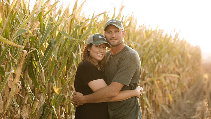 Hardings hugging standing by a row of corn