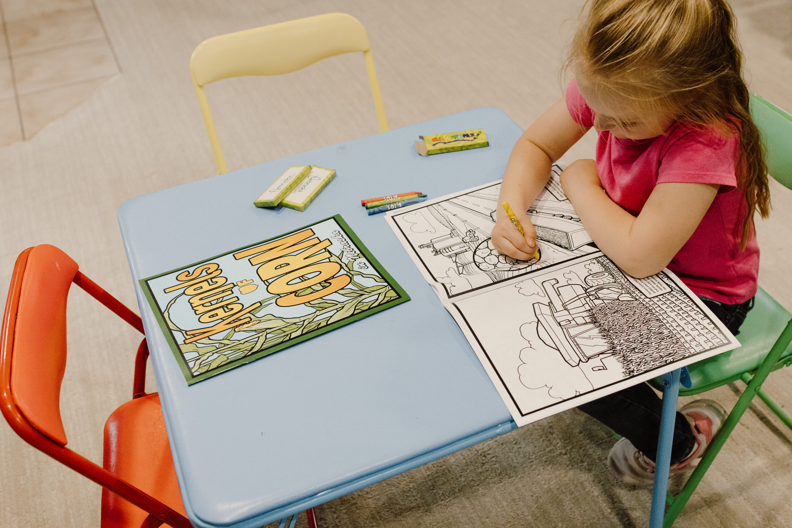 a little girl coloring in a kernels of corn nebraska coloring book